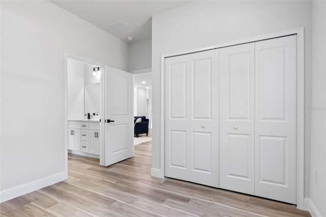 unfurnished bedroom with connected bathroom, a closet, light hardwood / wood-style floors, and sink