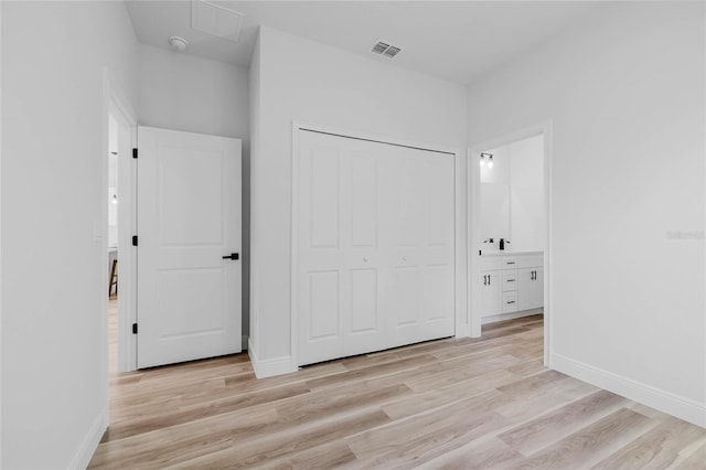 unfurnished bedroom featuring light wood-type flooring, connected bathroom, and a closet