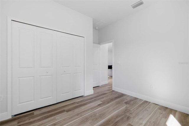 unfurnished bedroom featuring light wood-type flooring and a closet