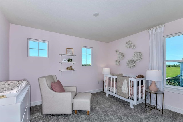 bedroom featuring a nursery area and dark carpet