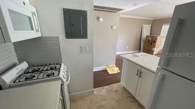 kitchen featuring light hardwood / wood-style flooring, electric panel, white appliances, white cabinets, and ornamental molding