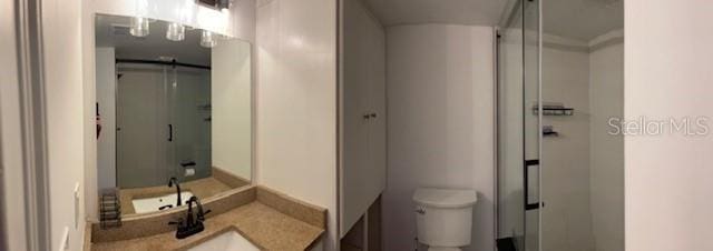 bathroom featuring an enclosed shower, vanity, and toilet