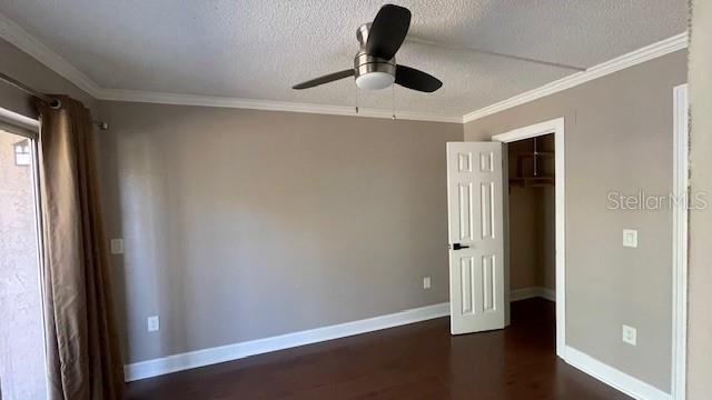 unfurnished bedroom featuring ceiling fan, dark hardwood / wood-style floors, ornamental molding, a textured ceiling, and a closet