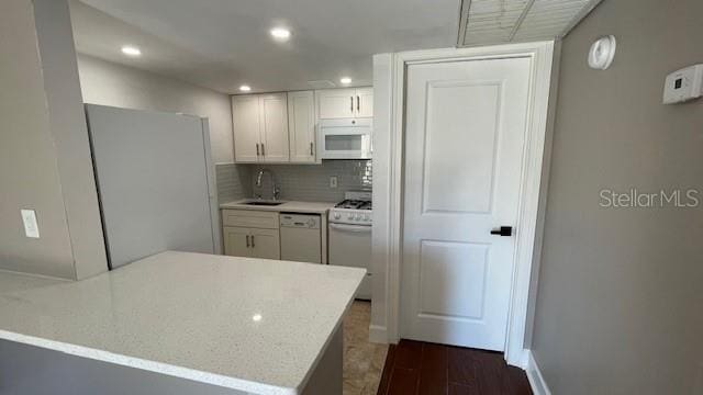 kitchen featuring sink, dark wood-type flooring, kitchen peninsula, white appliances, and white cabinets