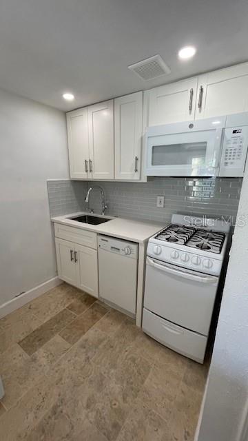 kitchen with white cabinets, decorative backsplash, white appliances, and sink