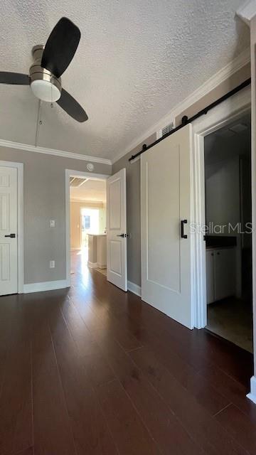 empty room with dark hardwood / wood-style floors, a barn door, and a textured ceiling