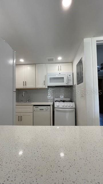 kitchen with sink, white appliances, white cabinetry, and backsplash