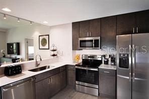 kitchen featuring rail lighting, sink, light hardwood / wood-style flooring, dark brown cabinetry, and stainless steel appliances