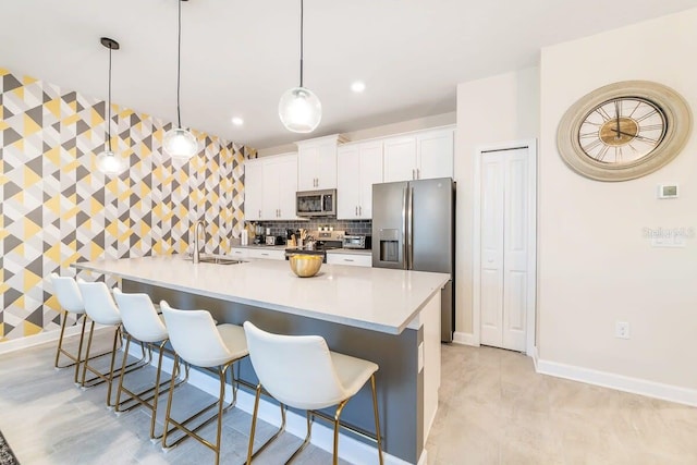 kitchen featuring appliances with stainless steel finishes, a breakfast bar, sink, white cabinets, and hanging light fixtures