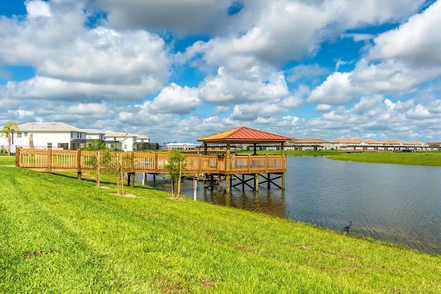 dock area with a gazebo, a yard, and a water view