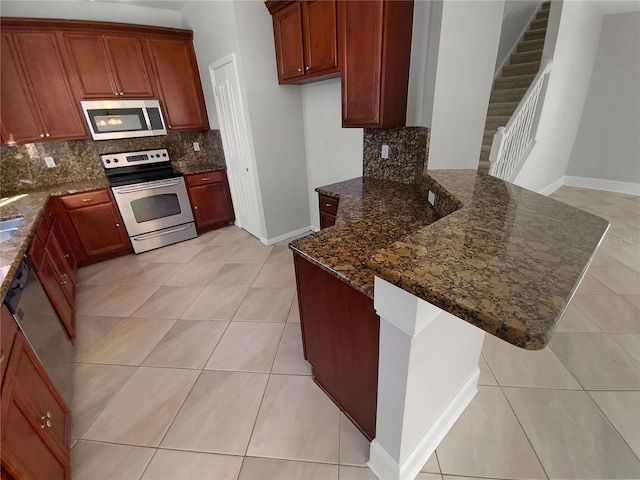 kitchen with light tile patterned floors, stainless steel appliances, tasteful backsplash, and dark stone counters