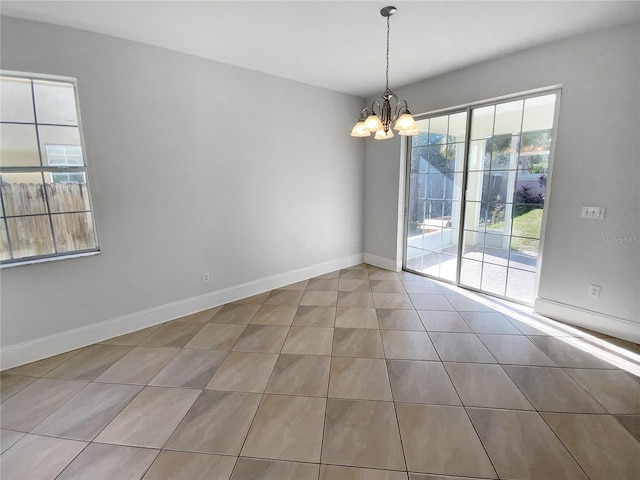 unfurnished room with tile patterned floors, a healthy amount of sunlight, and a chandelier