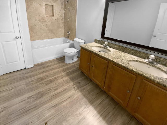 full bathroom featuring hardwood / wood-style floors, vanity, toilet, and tiled shower / bath