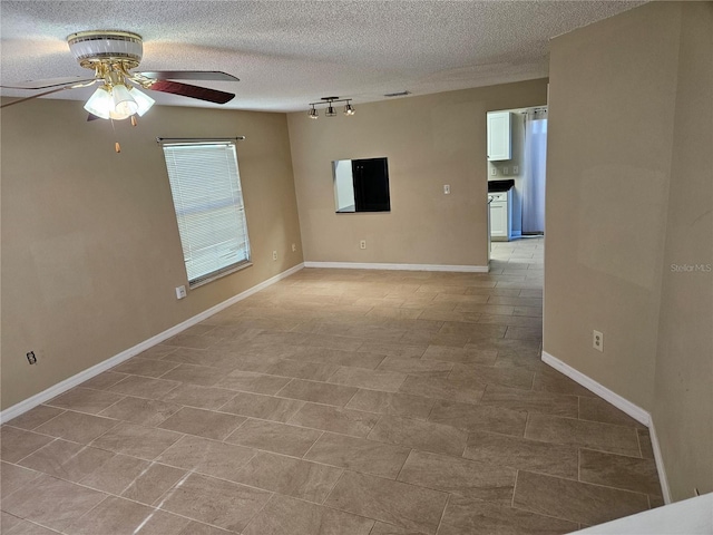 empty room with ceiling fan, track lighting, and a textured ceiling