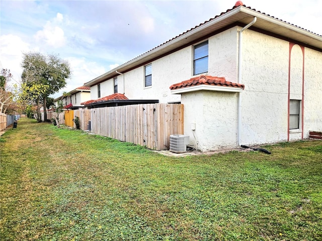 view of property exterior featuring central AC unit and a lawn