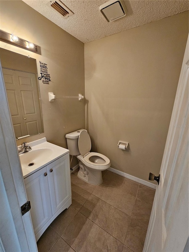 bathroom with vanity, toilet, tile patterned flooring, and a textured ceiling