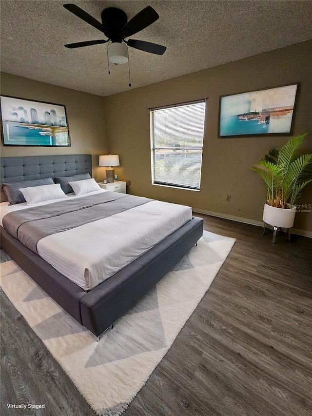 bedroom with ceiling fan, dark wood-type flooring, and a textured ceiling