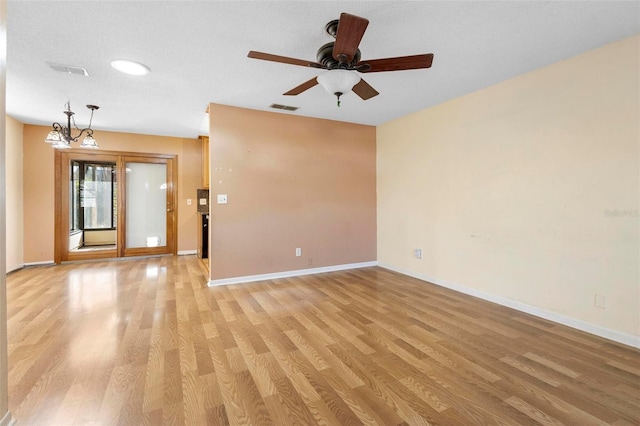 unfurnished living room featuring a textured ceiling, ceiling fan with notable chandelier, and light hardwood / wood-style floors