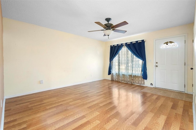 foyer entrance featuring ceiling fan, a textured ceiling, and light hardwood / wood-style flooring