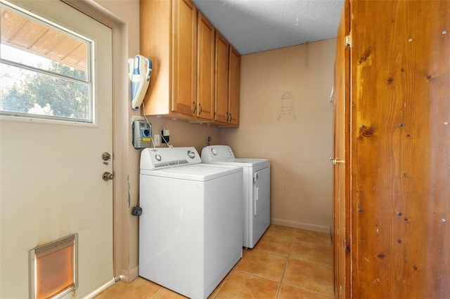 laundry room with light tile patterned flooring, cabinets, separate washer and dryer, and a textured ceiling