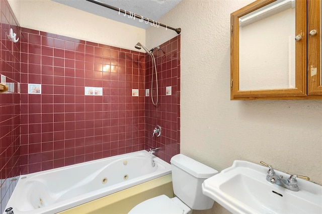 full bathroom featuring toilet, sink, a textured ceiling, and tiled shower / bath