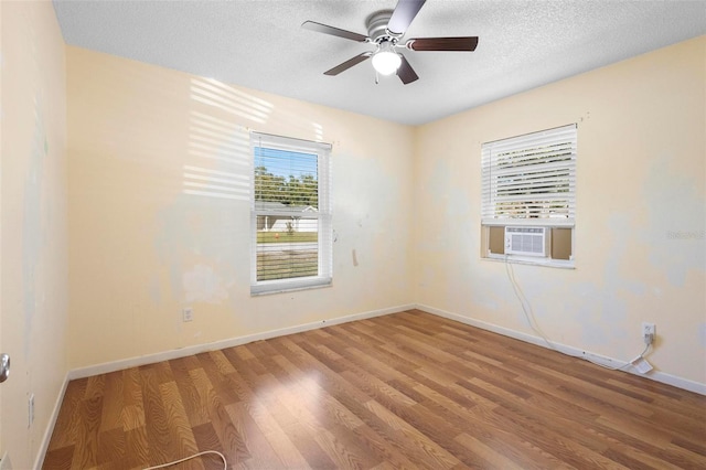 empty room featuring hardwood / wood-style floors, ceiling fan, cooling unit, and a textured ceiling