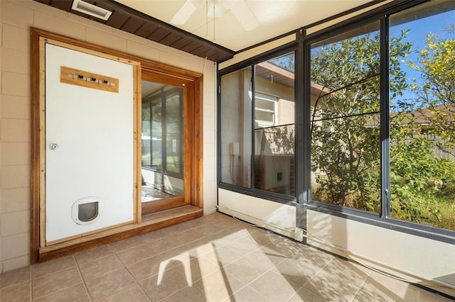 unfurnished sunroom featuring ceiling fan and a healthy amount of sunlight