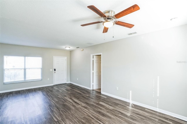 spare room featuring ceiling fan, dark wood-type flooring, and a textured ceiling