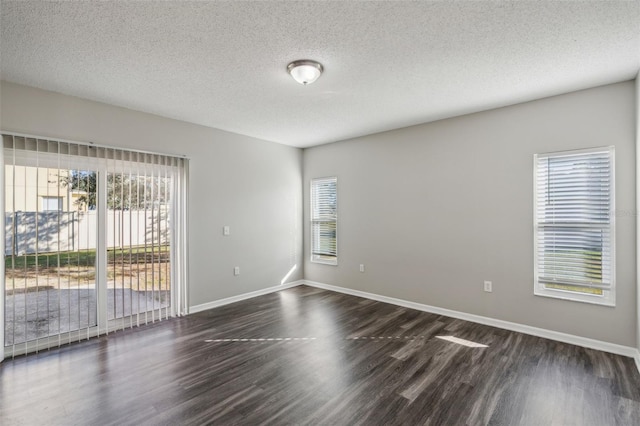 empty room with dark wood-type flooring and a textured ceiling