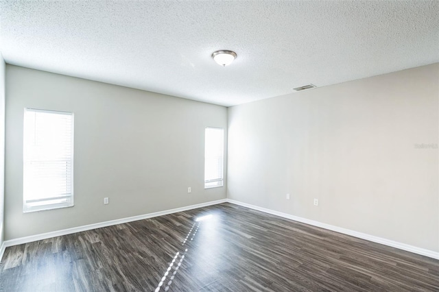 empty room featuring dark hardwood / wood-style flooring and a textured ceiling