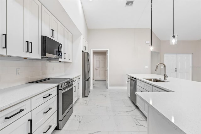 kitchen with light stone countertops, stainless steel appliances, sink, decorative light fixtures, and white cabinets