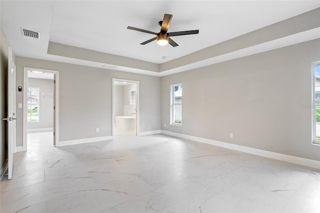 spare room featuring ceiling fan, a healthy amount of sunlight, and a tray ceiling