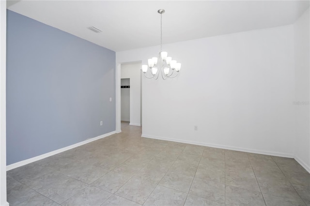 tiled spare room with an inviting chandelier