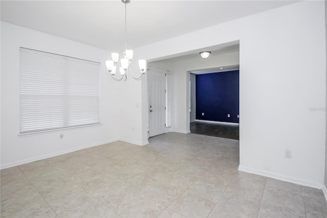 tiled empty room featuring an inviting chandelier