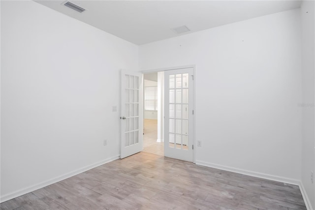 empty room featuring french doors and light hardwood / wood-style flooring