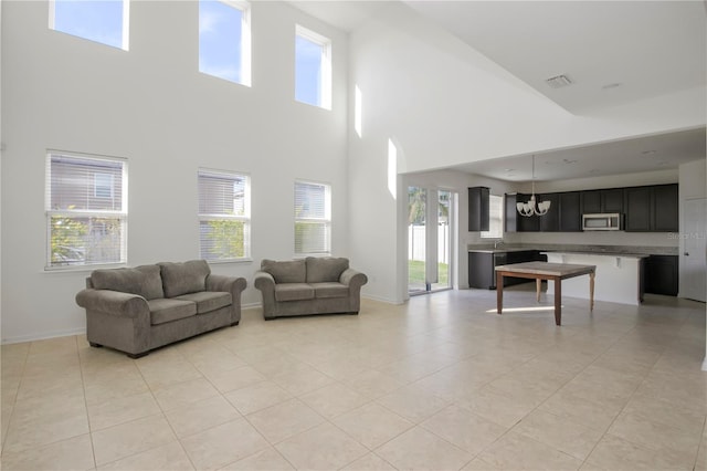 living room featuring light tile patterned floors, a high ceiling, and an inviting chandelier