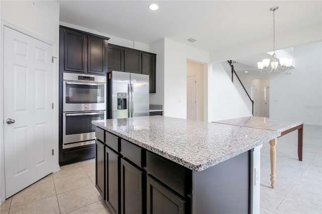 kitchen featuring pendant lighting, light stone counters, stainless steel appliances, and a chandelier