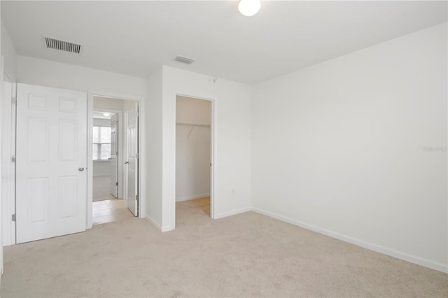 unfurnished bedroom featuring light colored carpet, a spacious closet, and a closet