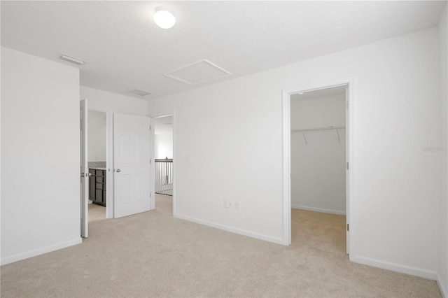 unfurnished bedroom featuring light carpet, a walk in closet, and a closet