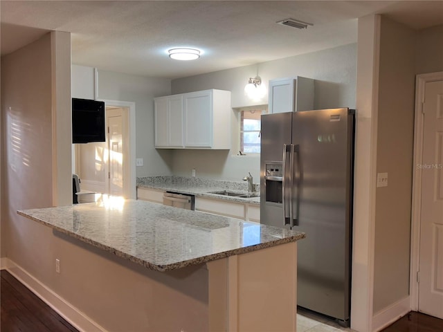 kitchen with white cabinetry, light wood-type flooring, light stone countertops, and stainless steel appliances