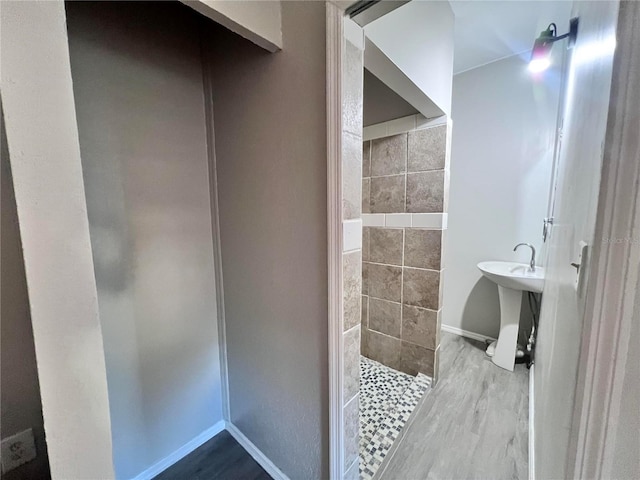 bathroom with tiled shower, hardwood / wood-style floors, and sink