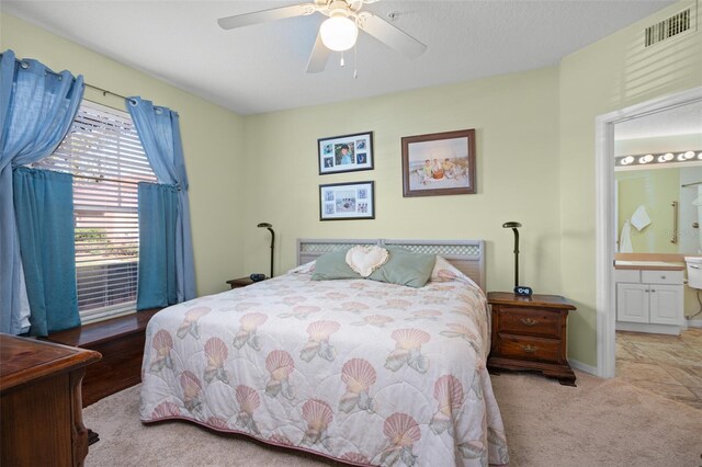 carpeted bedroom with ensuite bath and ceiling fan