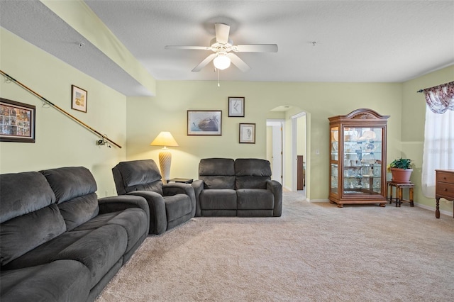 carpeted living room featuring ceiling fan and a textured ceiling