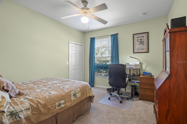 bedroom with a textured ceiling, light colored carpet, and ceiling fan