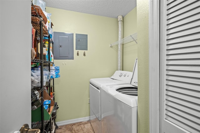 laundry room featuring light tile patterned flooring, a textured ceiling, electric panel, and washing machine and clothes dryer