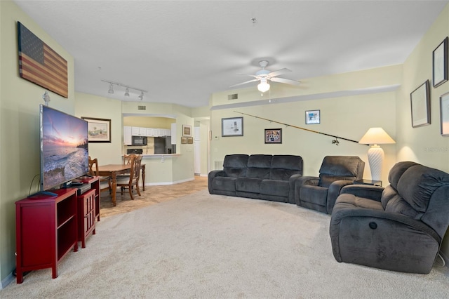 carpeted living room with track lighting and ceiling fan