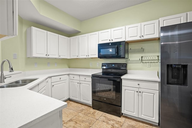 kitchen featuring black appliances, white cabinetry, sink, and light tile patterned floors