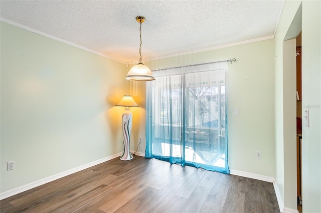 empty room with hardwood / wood-style floors, ornamental molding, and a textured ceiling