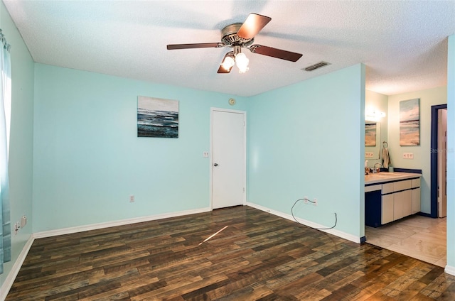 spare room with a textured ceiling, dark hardwood / wood-style flooring, ceiling fan, and sink