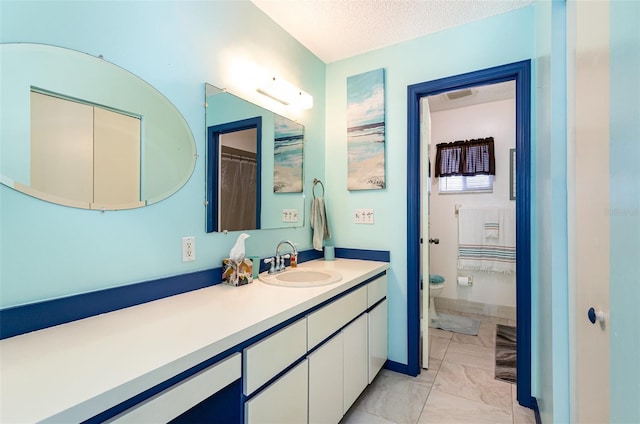 bathroom with vanity, toilet, and a textured ceiling